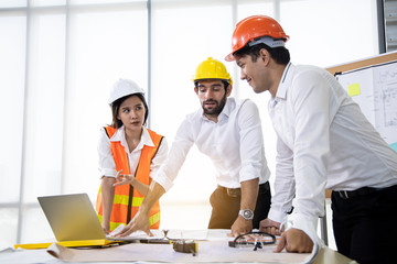 Three architects in the office and discussing design project.