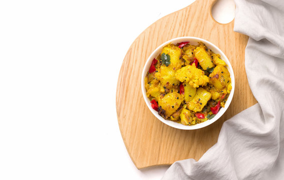 gobi aloo traditional indian vegetarian dish of potatoes and cauliflower in a plate on a white background. Copy space.