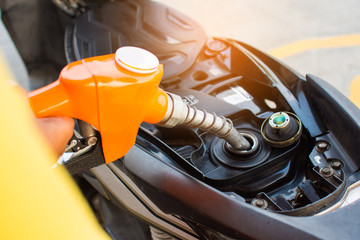 Refuel the motorcycle at the gas station. Gas nozzle pumping gasoline into the tank at the gas...