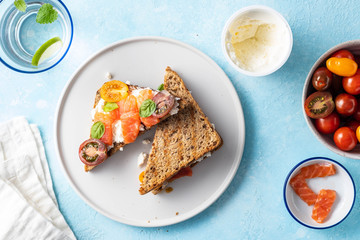 Delicious and tasty sandwich with salmon, basil, cherry tomatoes and caper. Close up selective focus. Traditional italian cuisine appetizer. Seafood. Food photo for menu or recipe. Top view flat lay