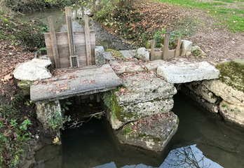 An ancient sluice made with wood and stone in a little lake.