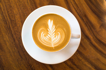 Latte art coffee in a white cup on a wooden table