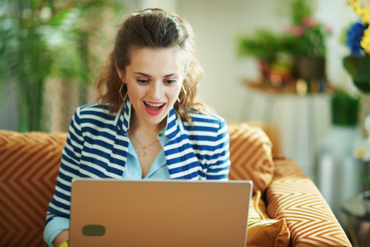 surprised woman with laptop in modern house in sunny day