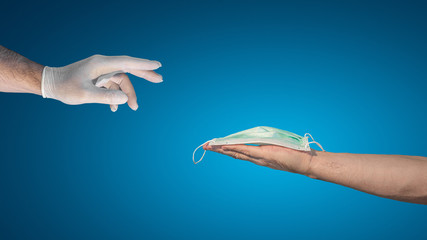Banner with a hand in medical glove trying to take a surgical mask from another hand, design concept with copy space for text at gradient blue background, details, closeup