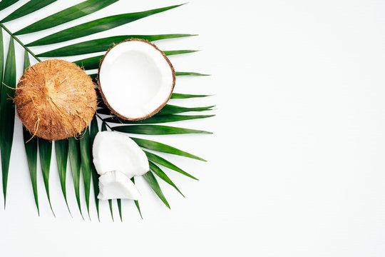 Coconut with palm leaf on white background. Flat lay, top view. Summer background with natural organic food