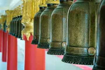 Row of large old traditional religious bells hanging in buddhist temple in Thailand