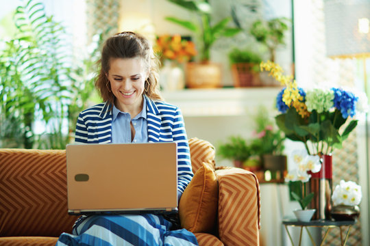 happy modern woman with laptop in modern house in sunny day