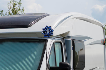 White house on wheels (camper) for travel with a pinwheel on a stick in the colors of the flag of the Republic of Estonia