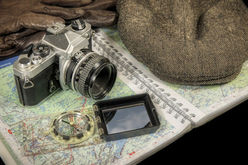 Vintage 35mm film camera with map, compass, hat and gloves in background - Powered by Adobe