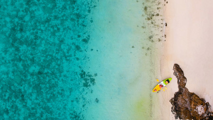 Aerial top view of clam clear sea in summer with kayak beside reef on white sand © Phonphot