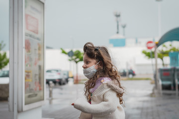 cute little girl wearing a  surgical mask is running happily outside of a supermarket