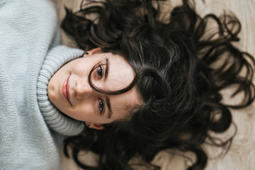 Close-up portrait of a charming European girl of 8 years old. She smiles lying on the floor. She has beautiful wavy, loose hair.