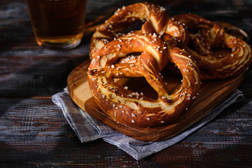 Freshly baked homemade soft pretzel with salt on wooden table. Perfect for Octoberfest. - obrazy, fototapety, plakaty