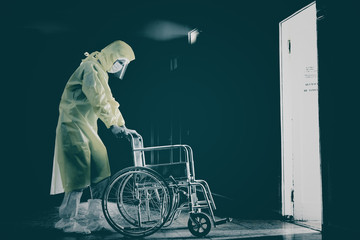 Doctor in a protective suit with wheelchair, covid-19 pandemic, horror.