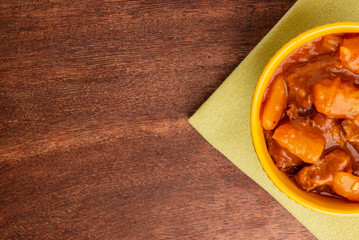 bowl with cooked cassava and meat on wooden table