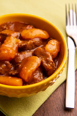 bowl with cooked cassava and meat on wooden table