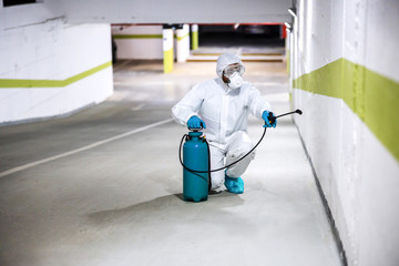 Worker in sterile uniform and mask walking trough underground garage and surface door. Protection from corona virus / covid-19 concept.