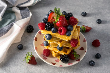 Traditional homemade Belgian waffles with fresh summer berries, blueberry raspberry, strawberry and blackberry. Delicious breakfast.