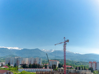 Tower crane, red against the sky and mountains