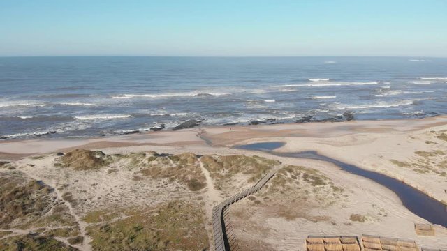 DRONE - view of dune fencing to control wind erosion and encourage dune stability. Stream flowing into the sea at the North Coast Natural Park, The Protected Landscape of Esposende Coast, Portugal.