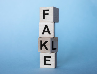 fake and fale inscription on wooden cubes on a bright blue background © valiantsin