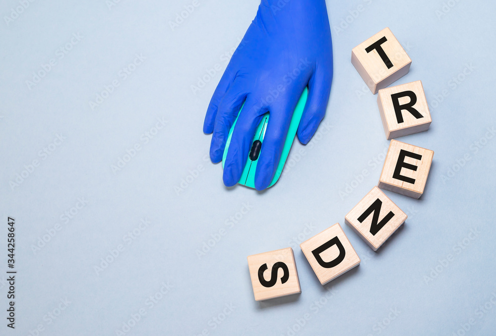 Poster trends word on cube blocks. the hand in protective glove using a computer mouse on blue table. preve