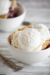 Fresh made homemade cherry cobbler served with two scoops of vanilla ice cream. Selective focus with blurred background.