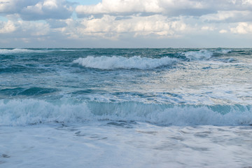 Naklejka na ściany i meble Blue sea with waves and sky with clouds before storm.