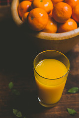 Amazing orange juice on the rustic wood table. We could see fresh oranges fruit on the background.