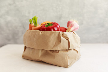 Paper grocery bag with fruits and vegetables over white background, eco shopping, zero waste, vegetarian concept