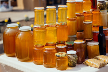 Jars full with different types of pure, raw,  fresh honey. Many glass with containers of different...