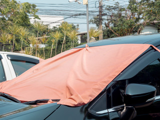 Red fabric covered on car front window for heat protection from sunshine.