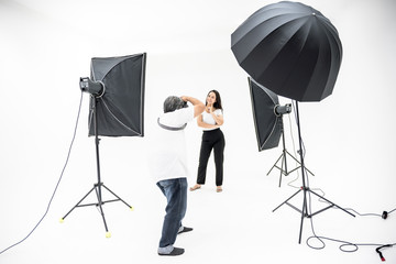 A man photographers are shooting pretty women in the studio with lighting equipment, To get a perfact and beautiful image, to the work of a professional photographer concept.