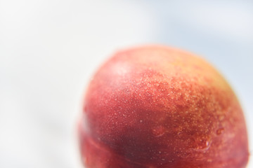 red skin of the peach with the drop of water on it. white background