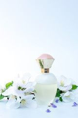 female perfume with spring flowers on light blue gradient background. concept of beauty and smell of spring