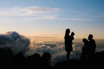 Silhouette of a woman and a man with their dogs in the cloud covered mountains