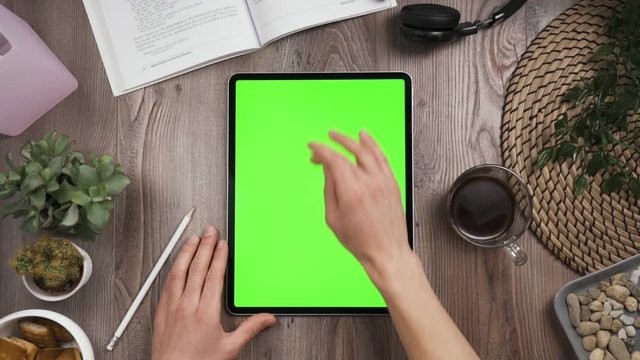 View from top on Big tab with green chroma key screen. Hand swipe up on touchscreen then two hands expressively shows thumb up. Tablet lay on the workplace table. Day time. 4k video.