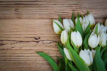 Top view of spring flowers tulips on a old vintage brown wooden background.