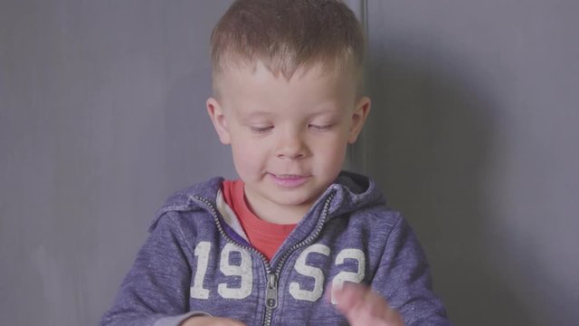 Funny Fun Three year old boy sculpting in plasticine on gray background
