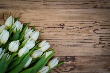 Top view of spring flowers tulips on a old vintage brown wooden background.