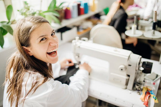 Excited creative tailor working on sewing machine.Handmade protective cotton masks making.DIY project,learning to sew on sewing machine.Sewing class.Craft hobby.Happy seamstress in apparel industry