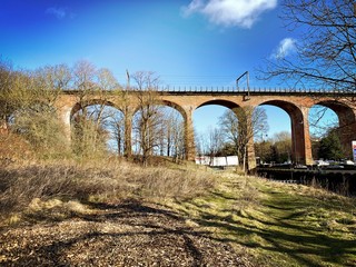 A scenic view of Chester Burn Railway Viaduct. Tall red brick arches cross Cong Burn stream in a small town in the North East of England. Built in 1868. Chester Le Street, County Durham, UK.