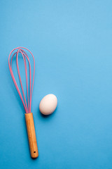 Kitchen whisk and a single egg, bake and cook concept