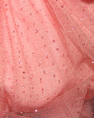 Textile background with pink tulle in sequins. Delicate fabric