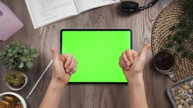 Big Tab With Green Chromakey Screen. Top View. Hand Taps On The Center Of Touchscreen Then Hands Show Forefingers To The Screen And Show Thumb Up. Workplace Table With Many Things. 4k Video.