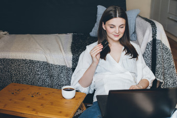 Young woman sitting on a couch and doing online shopping using her tablet and credit card. Social...