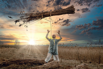 A man in a white protective overalls throws up a sheaf of hay. Virus attack.