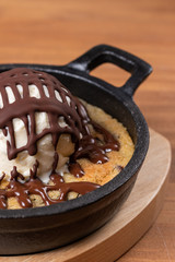 Delicious vanilla ice cream with chocolate syrup and cookie base.Wooden background