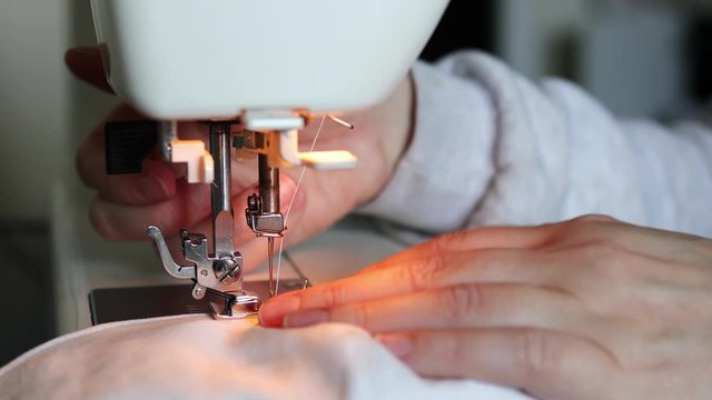 Close up video of woman using sewing machine at home for making protective mask
