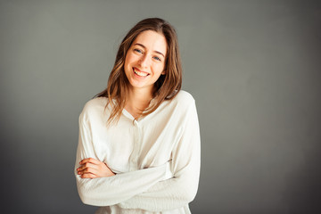 Obraz premium Young girl in a white shirt, hands up, on a gray background. Honest and emotional on the banner, billboard, billboard. No retouch. Without make-up.